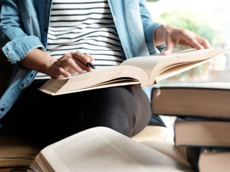 Femme se formant grâce à un livre en référence à la leçon n°2 de Sacheen ; toujours continuer d'apprendre.