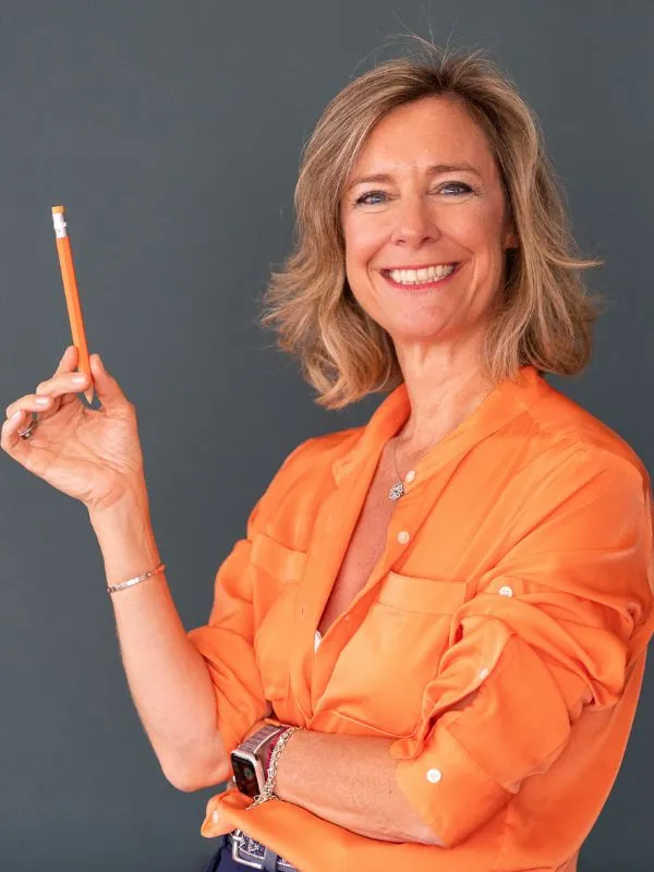 Photos de Sacheen Sierro souriante, tenant un crayon orange pour souligner l'importance d'une veille concurrentielle